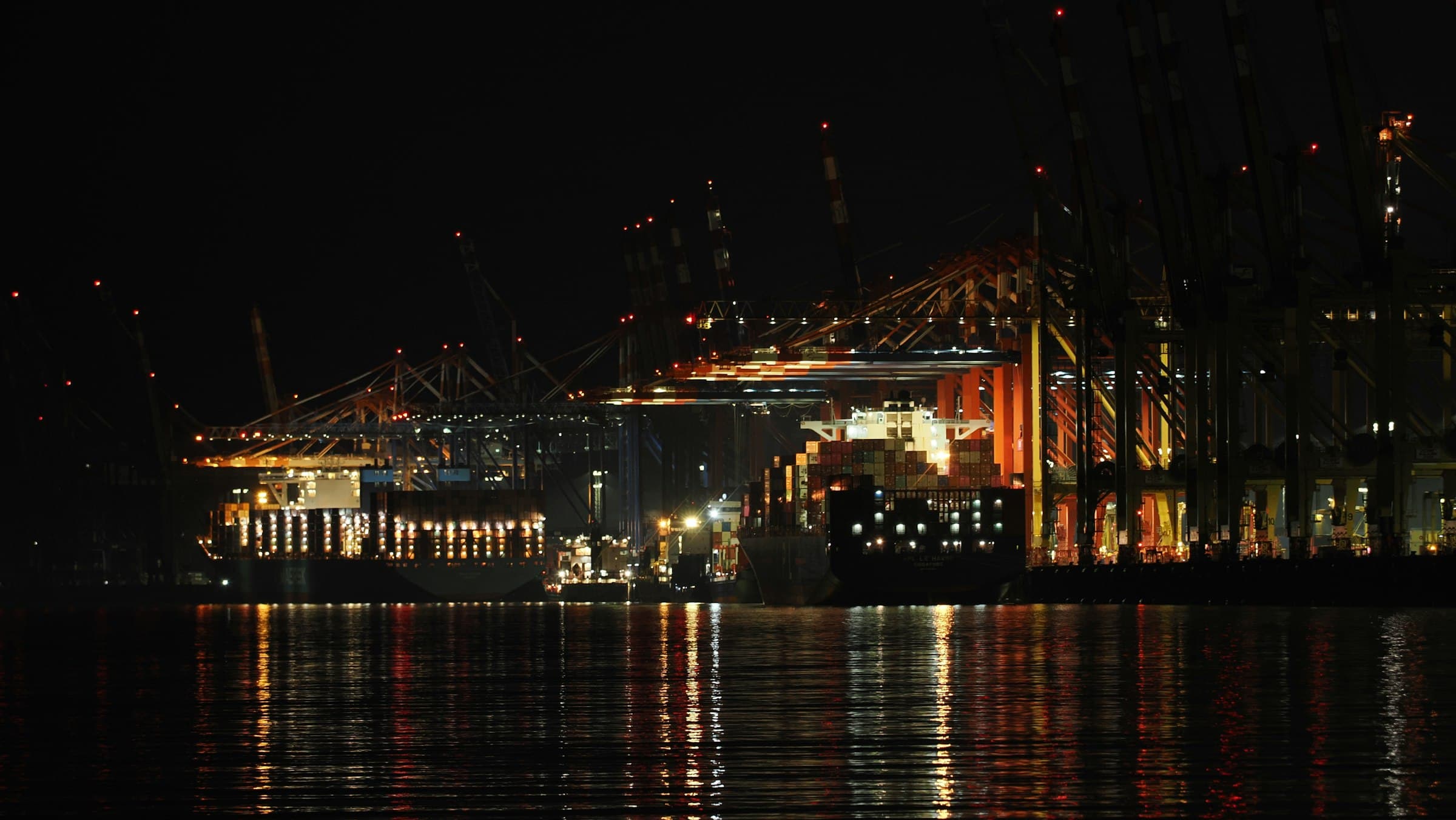 Container terminal at night with cranes lit above the water