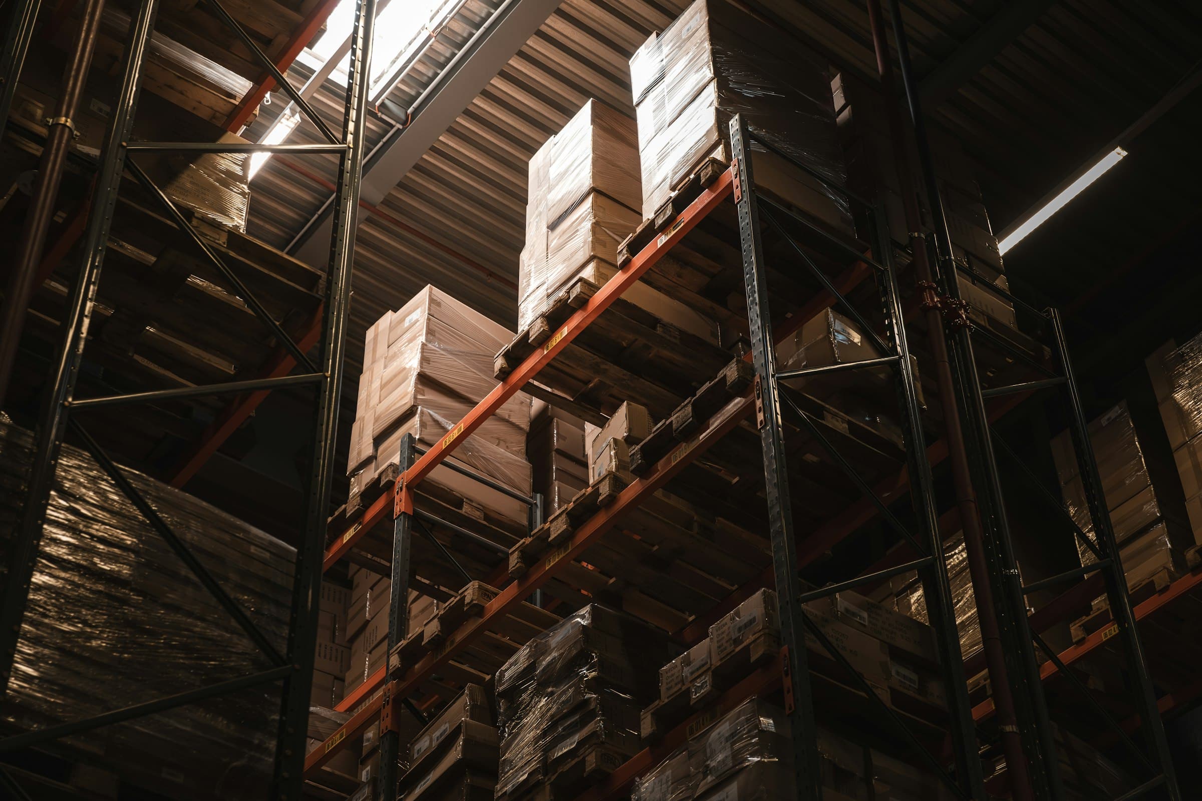 Tall warehouse racking with wrapped pallets in warm light