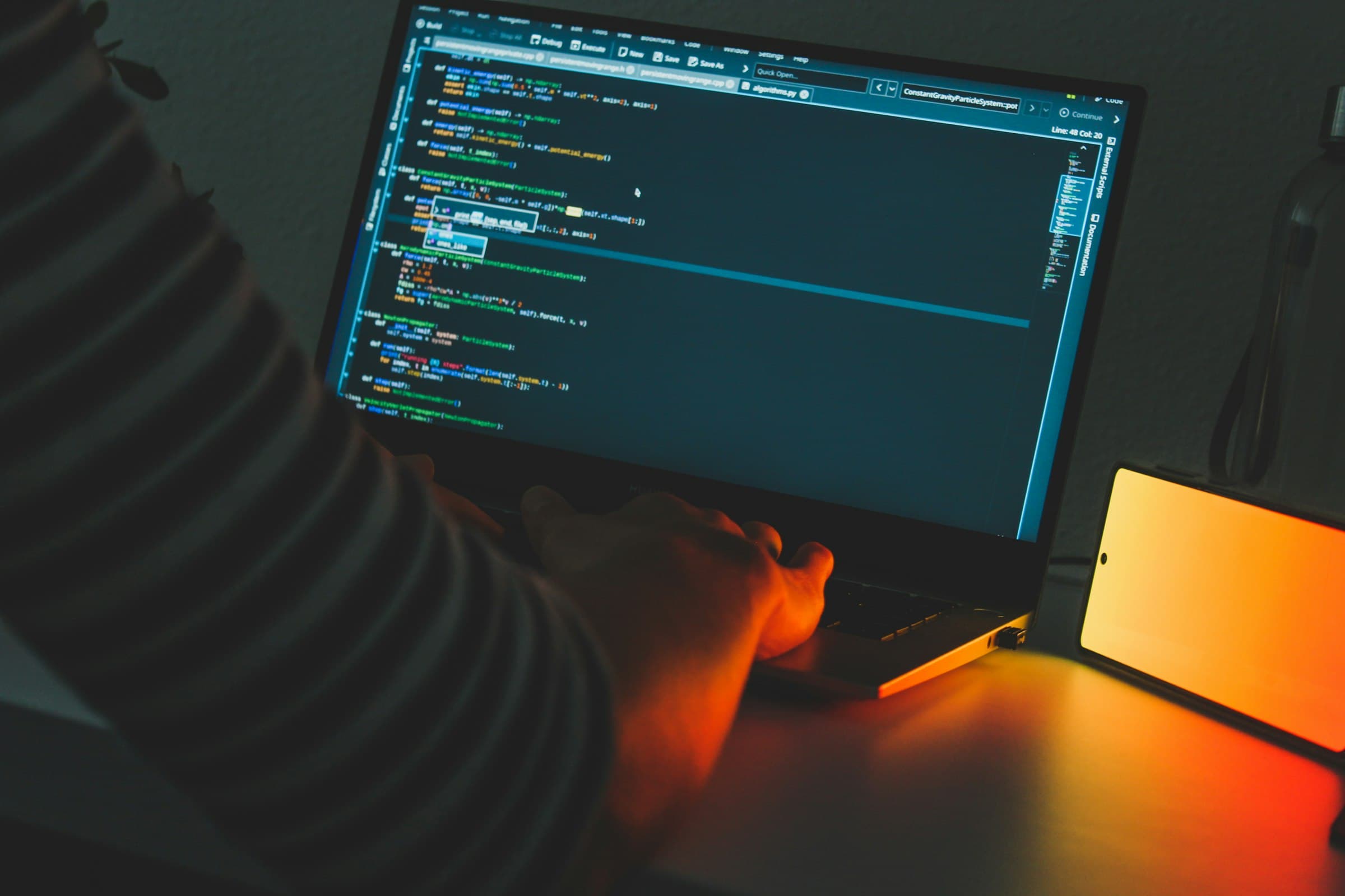 An engineer’s desk with code on screen in a dim, quiet room