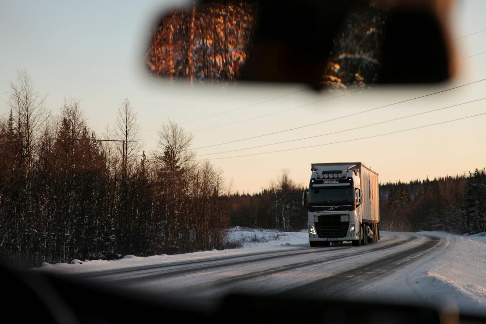 A truck on a snowy road seen through the windscreen of another truck